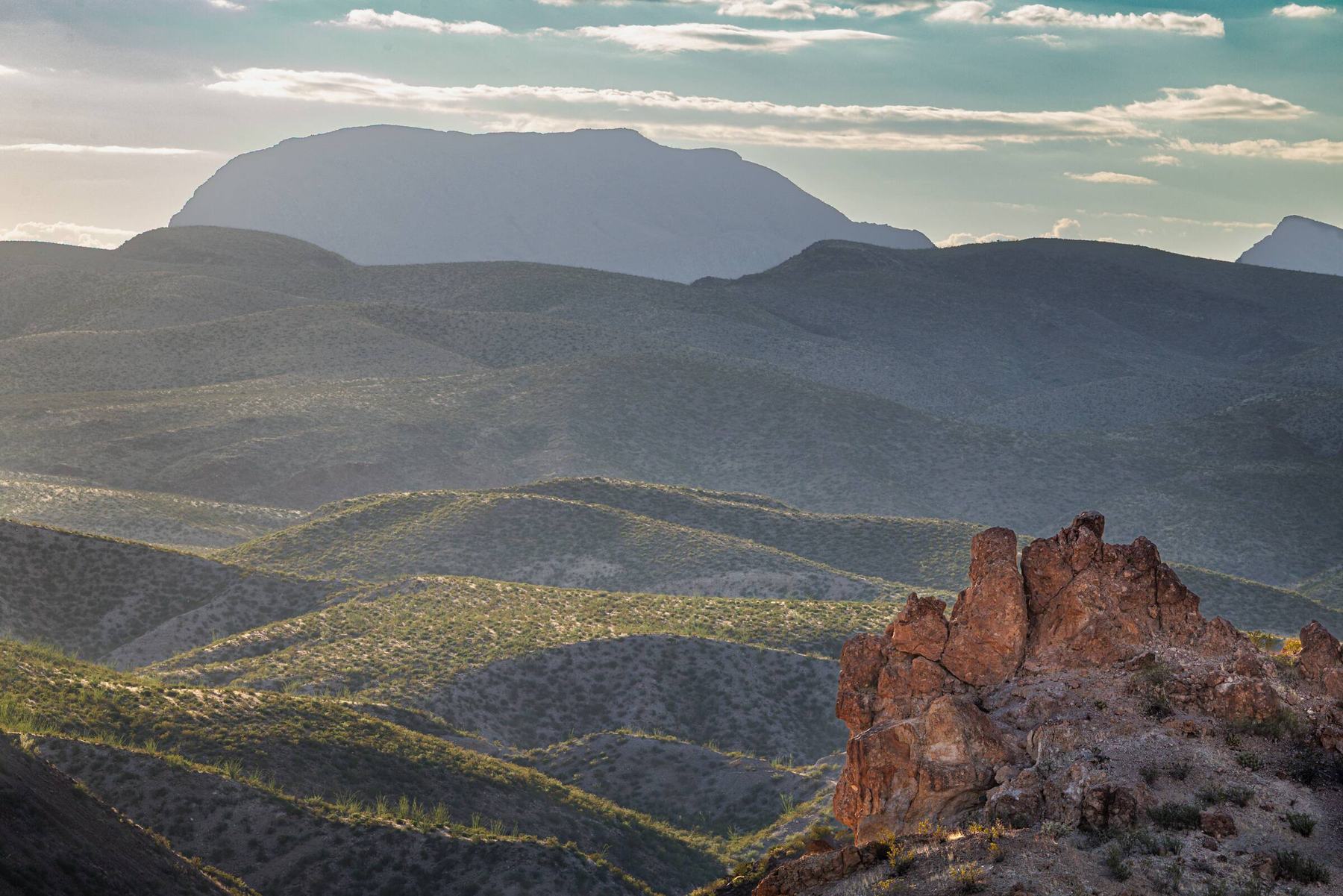 Rugged mountains and a red rock outcrop seen from Chispa Road