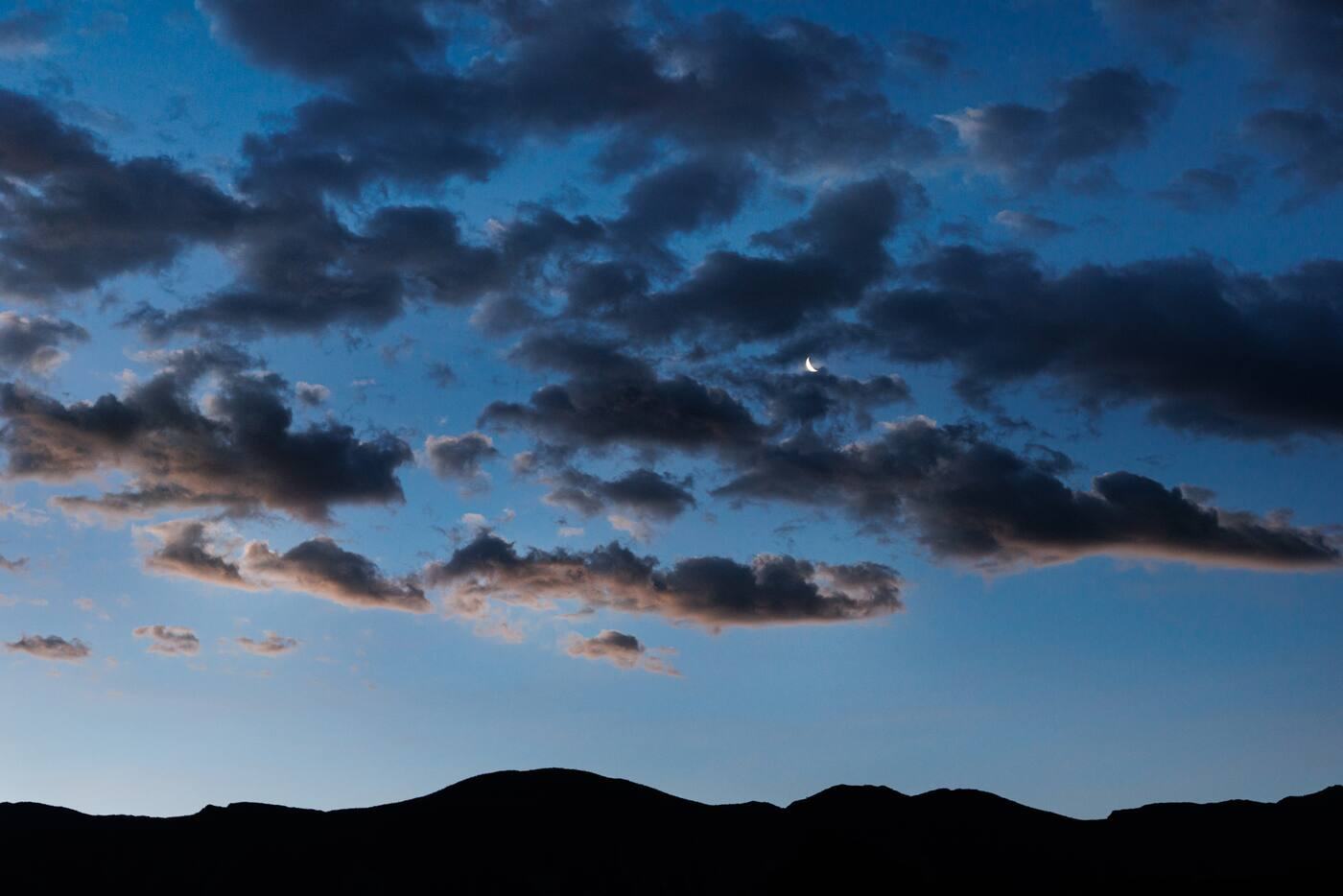 Clouds over dark mountain silhouettes at dawn