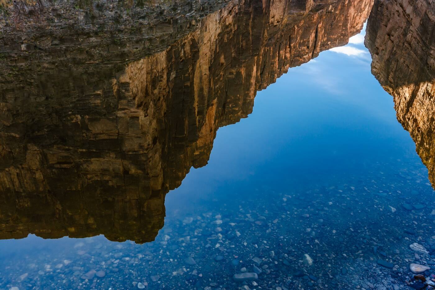 Canyon walls reflected in the still Rio Grande